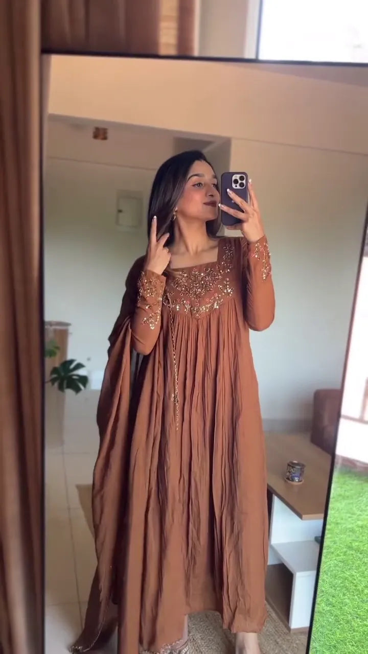 This is a stunning brown kurta with delicate embroidery around the neckline and sleeves. The outfit’s flowy silhouette paired with the graceful pleats