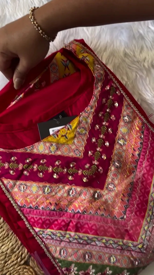 This outfit looks beautiful with its rich, deep red kurta paired with a vibrantly patterned dupatta. The geometric and floral designs on the dupatta in shades of pink, yellow