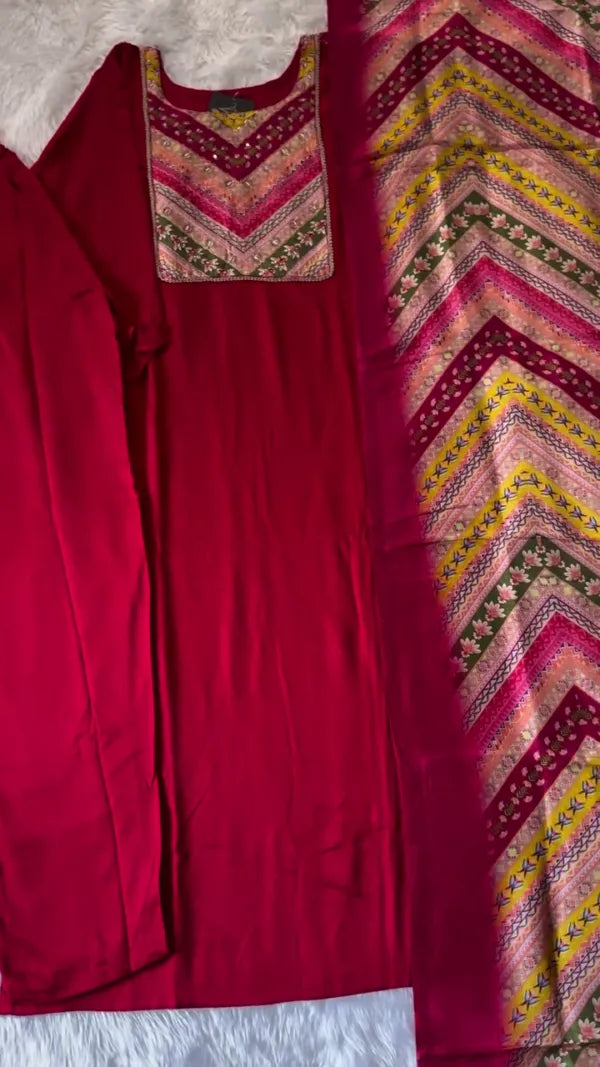 This outfit looks beautiful with its rich, deep red kurta paired with a vibrantly patterned dupatta. The geometric and floral designs on the dupatta in shades of pink, yellow